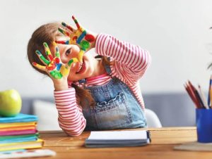 کودک در جلسه کاردرمانی در حال انجام بازی تقویت هماهنگی دو دست با لگو و قطعات رنگی