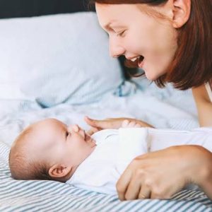 مادر در حال حرف زدن چهرهبهچهره با نوزاد خندان برای تقویت رشد زبان